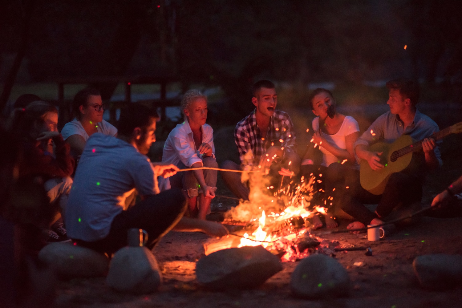 Un groupe de personnes riant et partageant des histoires autour d'un feu de camp dans un camping